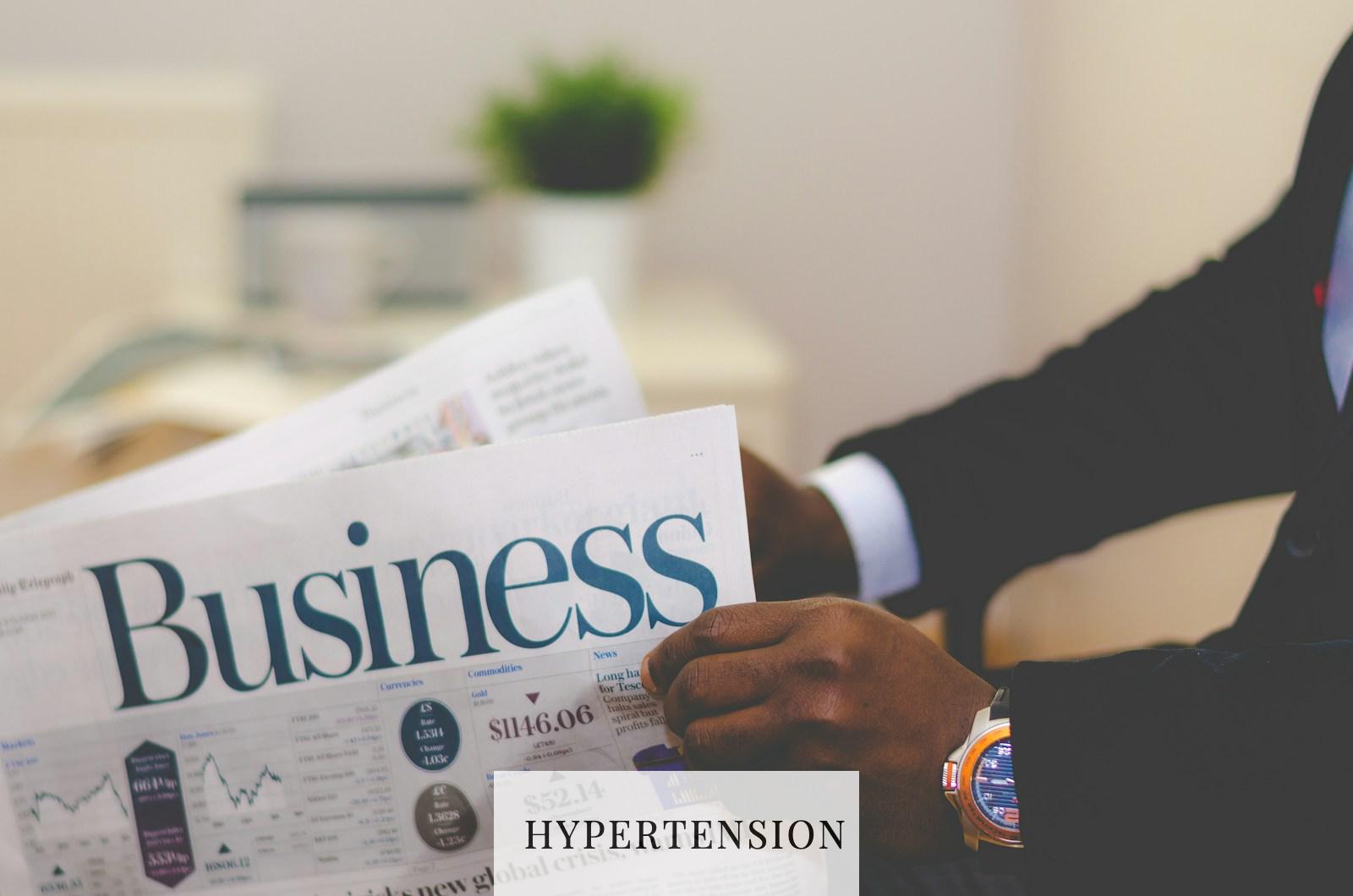 person wearing suit reading business newspaper
